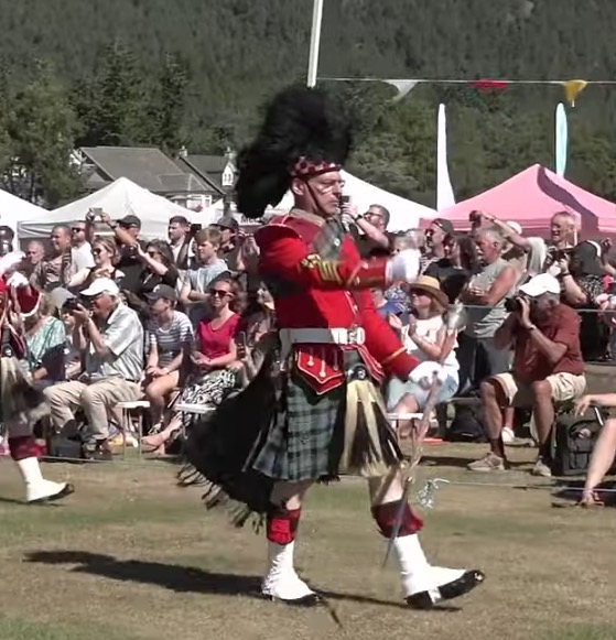 Drum Majors leading the Massed Pipe Bands on the march during 2022 Ballater Highland Games